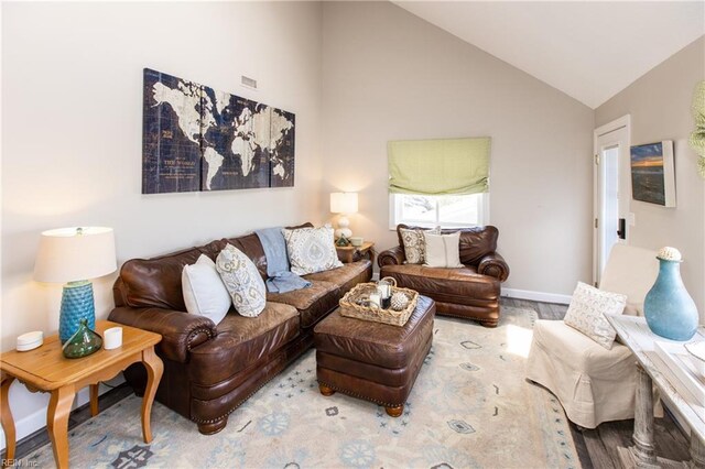 living room with visible vents, baseboards, vaulted ceiling, and wood finished floors
