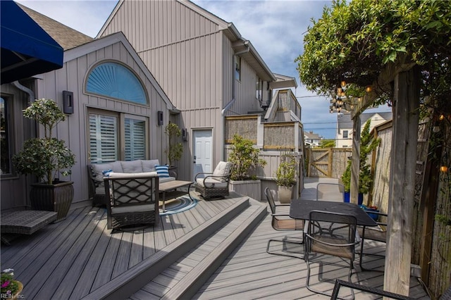 deck featuring outdoor lounge area, fence, and a gate