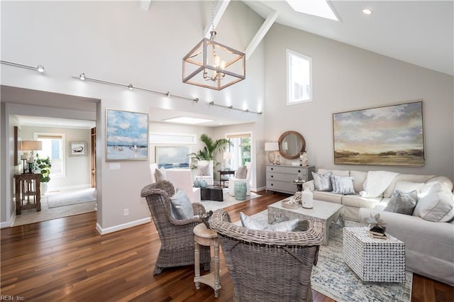 living area with wood finished floors, an inviting chandelier, baseboards, and high vaulted ceiling