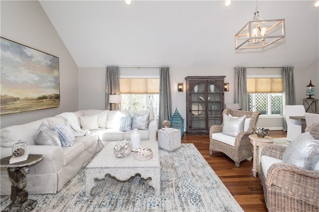 living room featuring an inviting chandelier, wood finished floors, vaulted ceiling, and a healthy amount of sunlight
