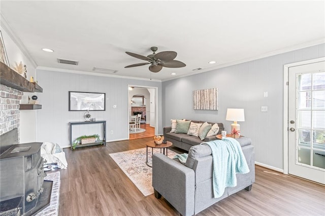 living area with visible vents, arched walkways, ornamental molding, a ceiling fan, and wood finished floors