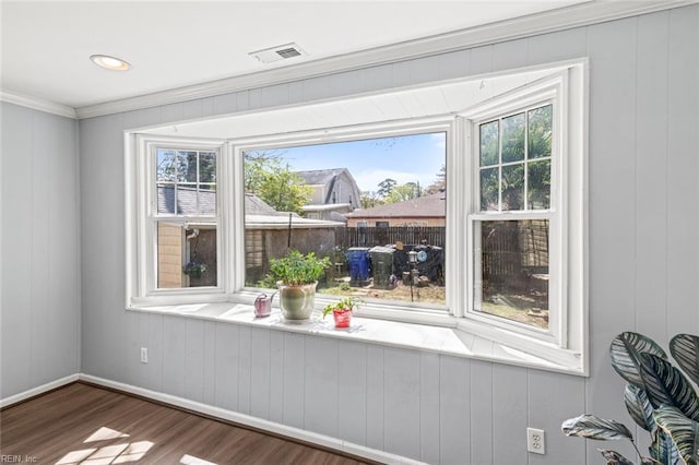 interior space with ornamental molding, visible vents, baseboards, and wood finished floors