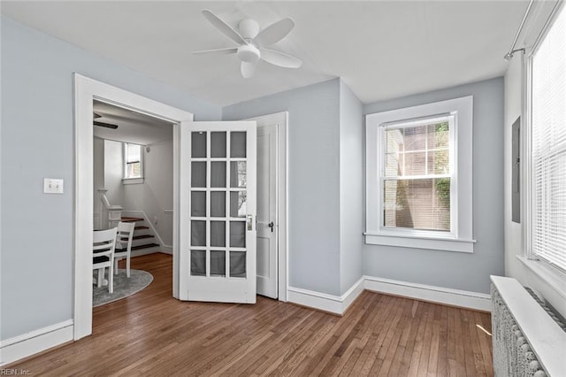 doorway to outside with ceiling fan, baseboards, radiator, and wood finished floors