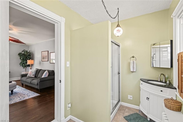 bathroom featuring a textured ceiling, vanity, wood finished floors, a stall shower, and baseboards
