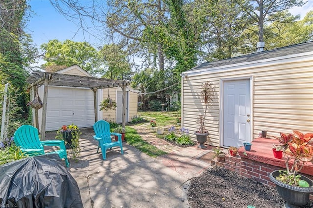 view of patio / terrace featuring an outbuilding, driveway, and a detached garage