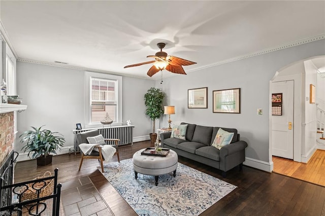 living area with baseboards, arched walkways, ceiling fan, hardwood / wood-style flooring, and crown molding