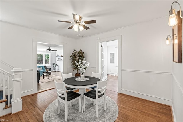 dining room featuring stairs, hardwood / wood-style floors, a ceiling fan, and crown molding