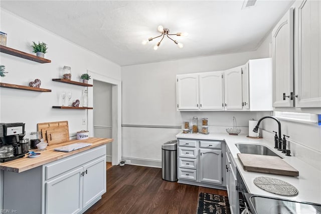 kitchen featuring open shelves, white cabinetry, a sink, wooden counters, and dark wood-style floors