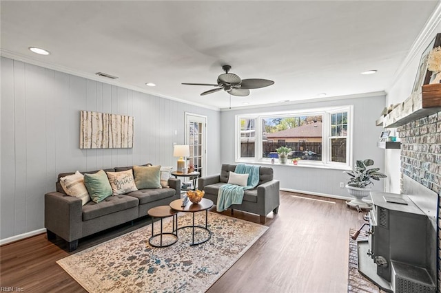 living room featuring visible vents, a brick fireplace, ornamental molding, a ceiling fan, and dark wood finished floors