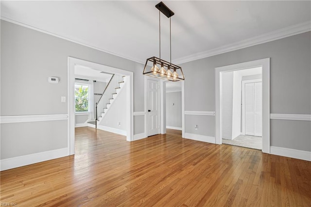 unfurnished dining area featuring crown molding, light wood finished floors, baseboards, and stairway
