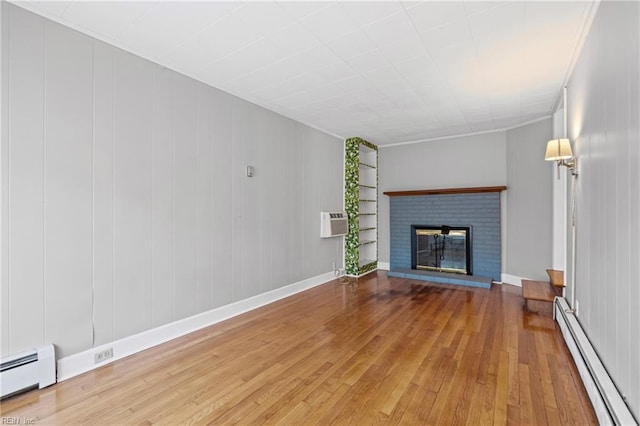 unfurnished living room featuring an AC wall unit, a baseboard radiator, hardwood / wood-style floors, and a brick fireplace