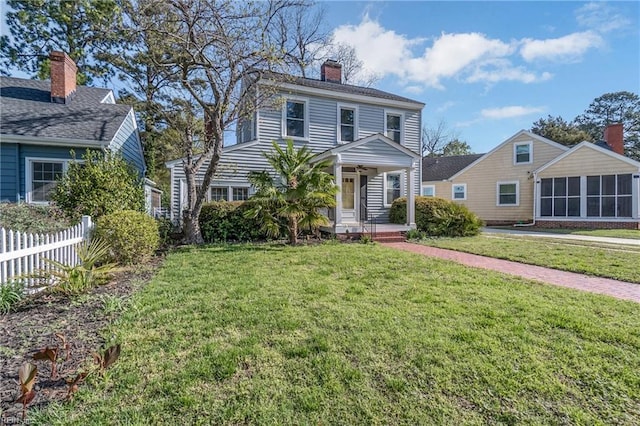 view of front of house featuring a front yard, fence, and a chimney