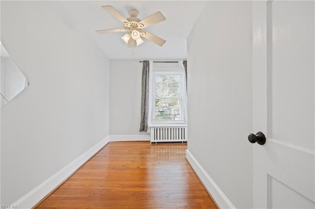 spare room with ceiling fan, wood finished floors, radiator heating unit, and baseboards