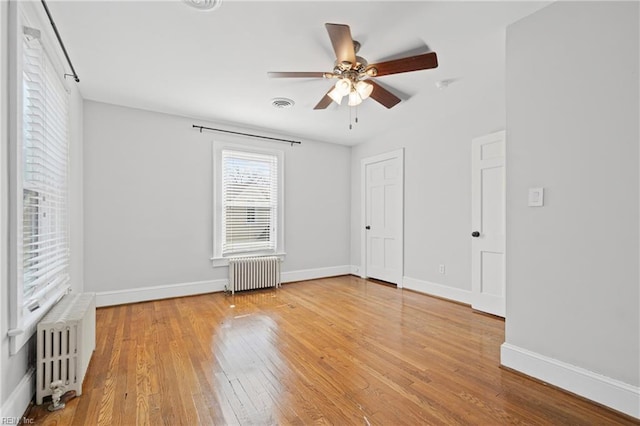 unfurnished bedroom featuring visible vents, radiator heating unit, hardwood / wood-style floors, and baseboards