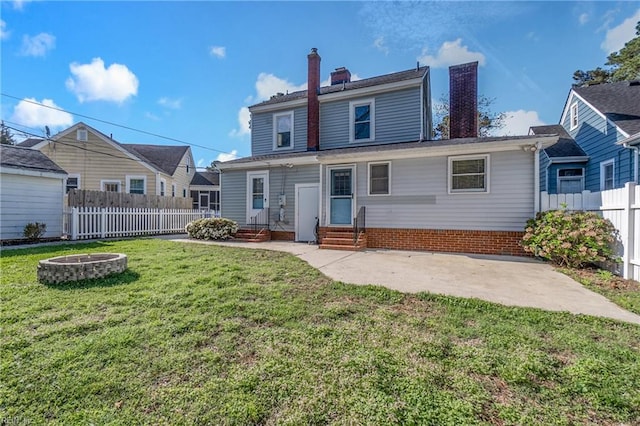 back of property featuring entry steps, an outdoor fire pit, a yard, a chimney, and fence private yard