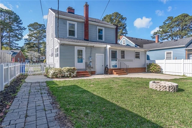 back of property featuring a yard, entry steps, a fenced backyard, and an outdoor fire pit