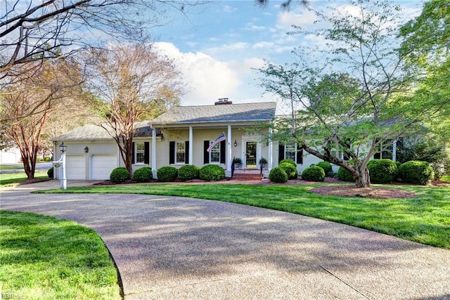 view of front facade with aphalt driveway, stucco siding, a front yard, a chimney, and a garage
