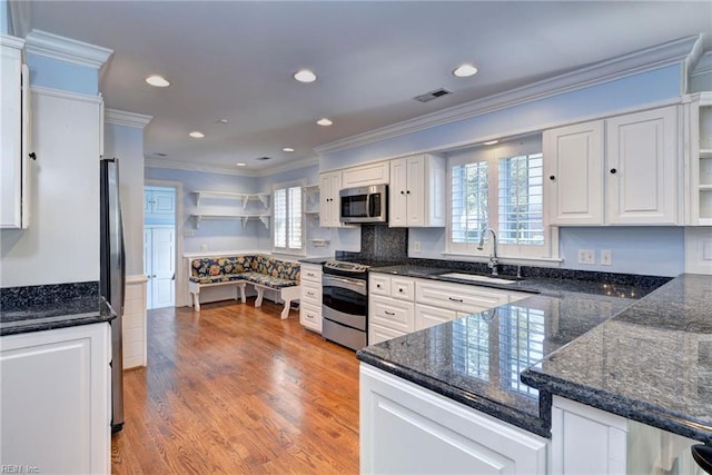 kitchen with a sink, ornamental molding, white cabinets, and appliances with stainless steel finishes