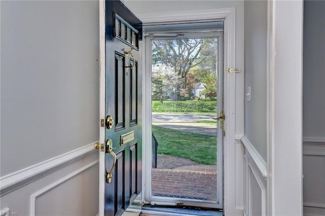 doorway featuring a decorative wall and wainscoting
