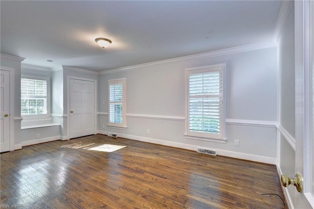 empty room featuring visible vents, ornamental molding, plenty of natural light, and wood finished floors