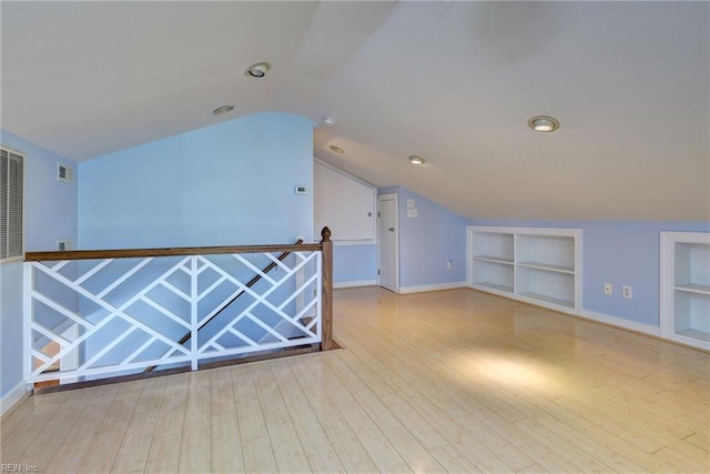 additional living space featuring visible vents, built in shelves, and wood finished floors