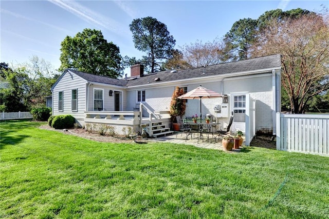 rear view of house with a lawn, a patio area, fence, a chimney, and a deck