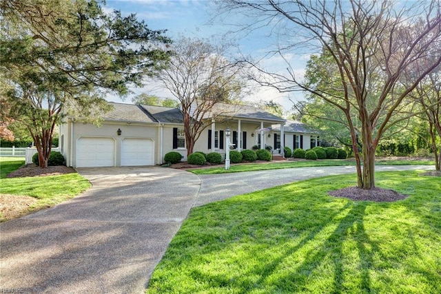 view of front of property with an attached garage, concrete driveway, stucco siding, and a front lawn