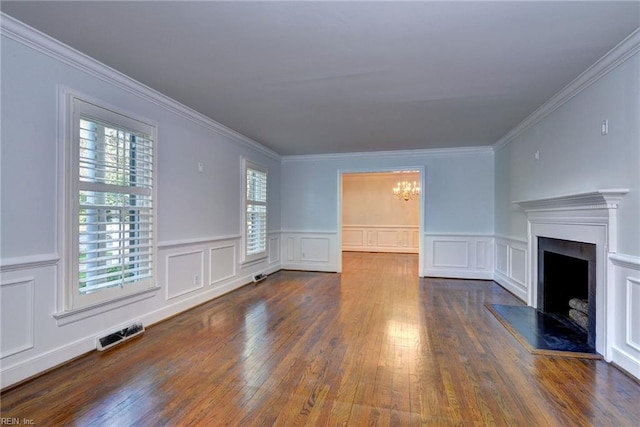 unfurnished living room with an inviting chandelier, ornamental molding, a fireplace with raised hearth, visible vents, and wood finished floors
