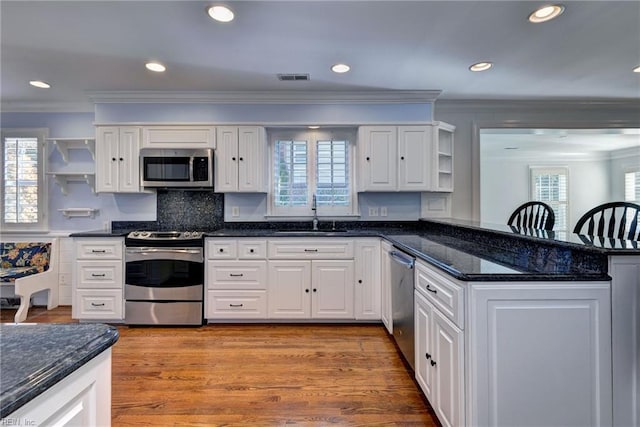kitchen featuring visible vents, open shelves, a sink, appliances with stainless steel finishes, and crown molding