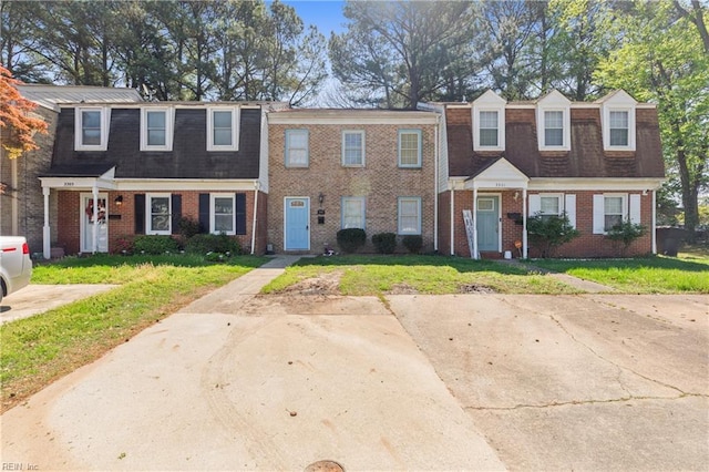 view of property with brick siding and a front yard