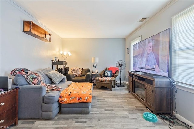 living area featuring visible vents, ornamental molding, baseboards, and light wood-style floors