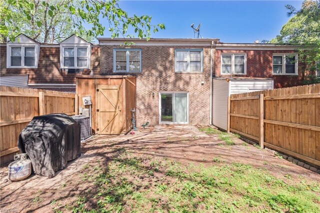 back of property featuring a fenced backyard, central AC unit, and brick siding
