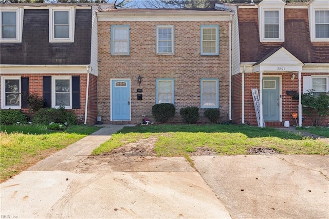 multi unit property featuring a front yard and brick siding