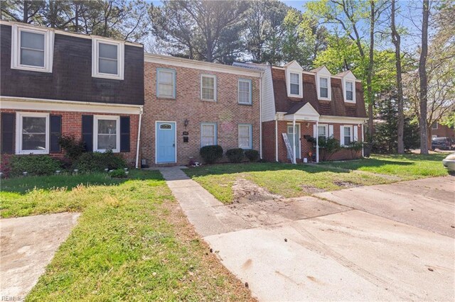 view of property featuring a front yard and brick siding