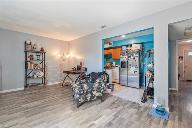living area featuring visible vents, baseboards, and light wood finished floors