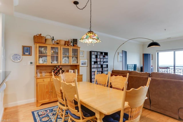 dining room with baseboards, light wood-style floors, and crown molding