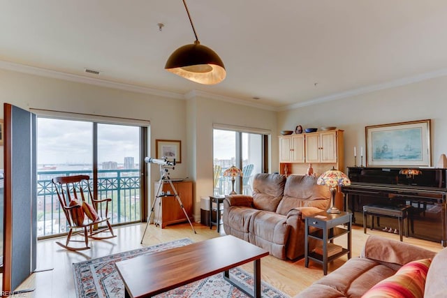 living area with crown molding, visible vents, and light wood-style flooring