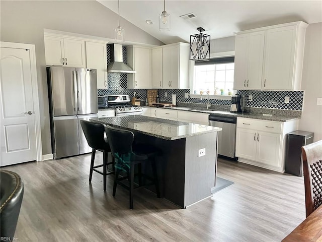 kitchen with appliances with stainless steel finishes, visible vents, wall chimney exhaust hood, decorative backsplash, and a sink