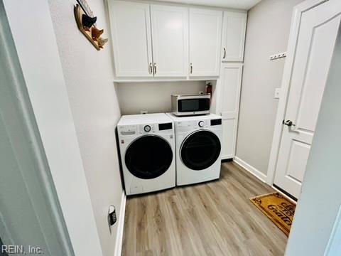 laundry area with light wood-type flooring, washing machine and dryer, baseboards, and cabinet space