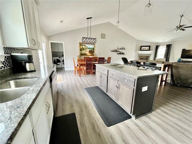 kitchen featuring visible vents, separate washer and dryer, a ceiling fan, light wood finished floors, and vaulted ceiling