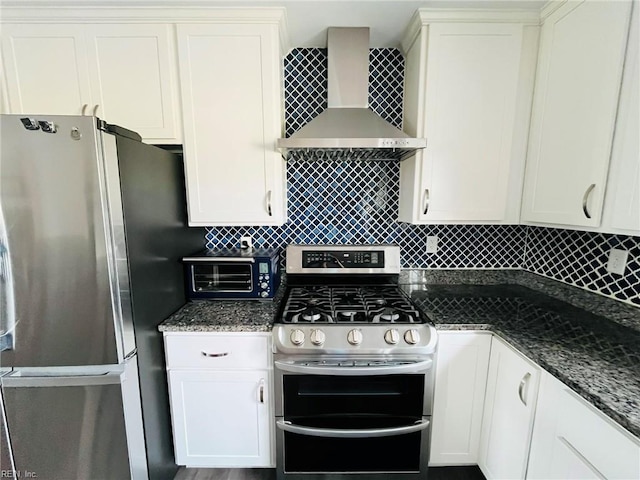 kitchen featuring wall chimney exhaust hood, appliances with stainless steel finishes, white cabinetry, decorative backsplash, and a toaster