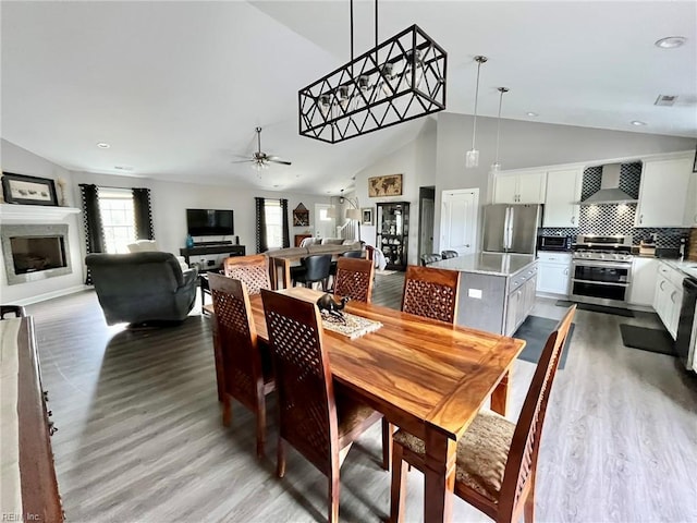 dining room featuring a glass covered fireplace, recessed lighting, light wood-style floors, and ceiling fan