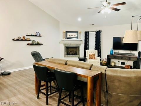 living room with light wood-style flooring, baseboards, vaulted ceiling, and ceiling fan