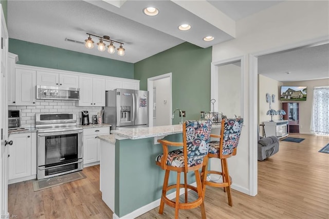 kitchen with light wood-style floors, white cabinetry, a peninsula, and stainless steel appliances