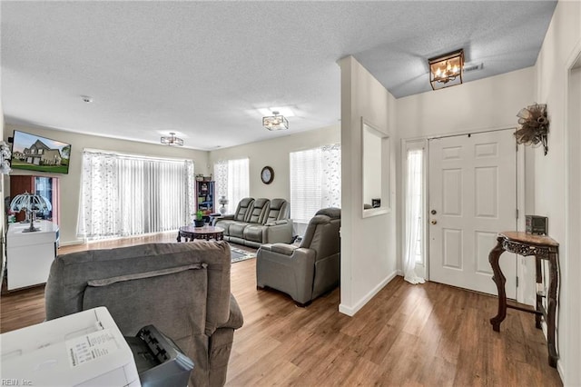 living area with a textured ceiling, baseboards, and wood finished floors