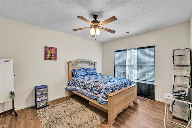 bedroom featuring a textured ceiling, wood finished floors, baseboards, and visible vents