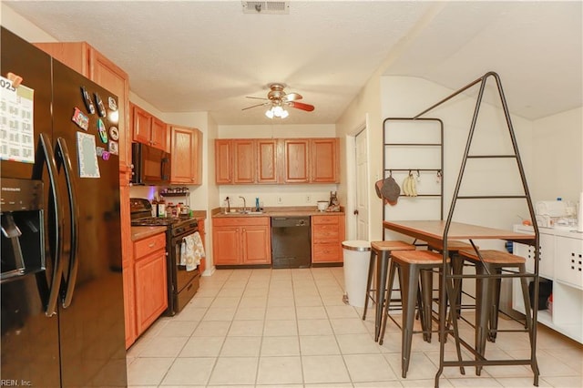 kitchen with visible vents, light tile patterned floors, a sink, a ceiling fan, and black appliances
