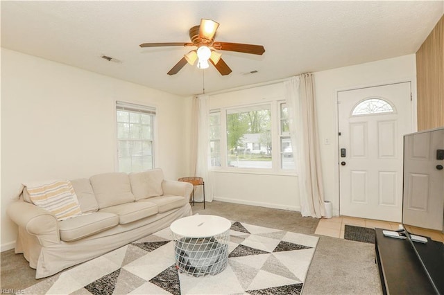 living area with plenty of natural light, visible vents, and ceiling fan