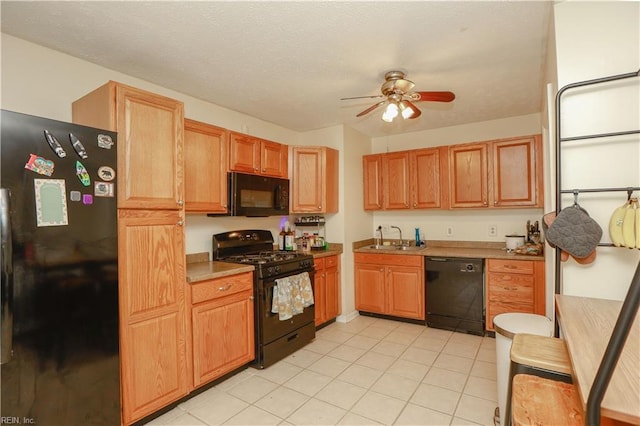 kitchen featuring light tile patterned floors, a ceiling fan, black appliances, light countertops, and a sink
