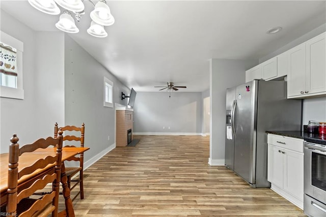 3410 E Princess Anne Rd, Norfolk, VA 23502 - kitchen featuring ceiling fan with notable chandelier, light wood-type flooring, white cabinetry, appliances with stainless steel finishes, and dark countertops